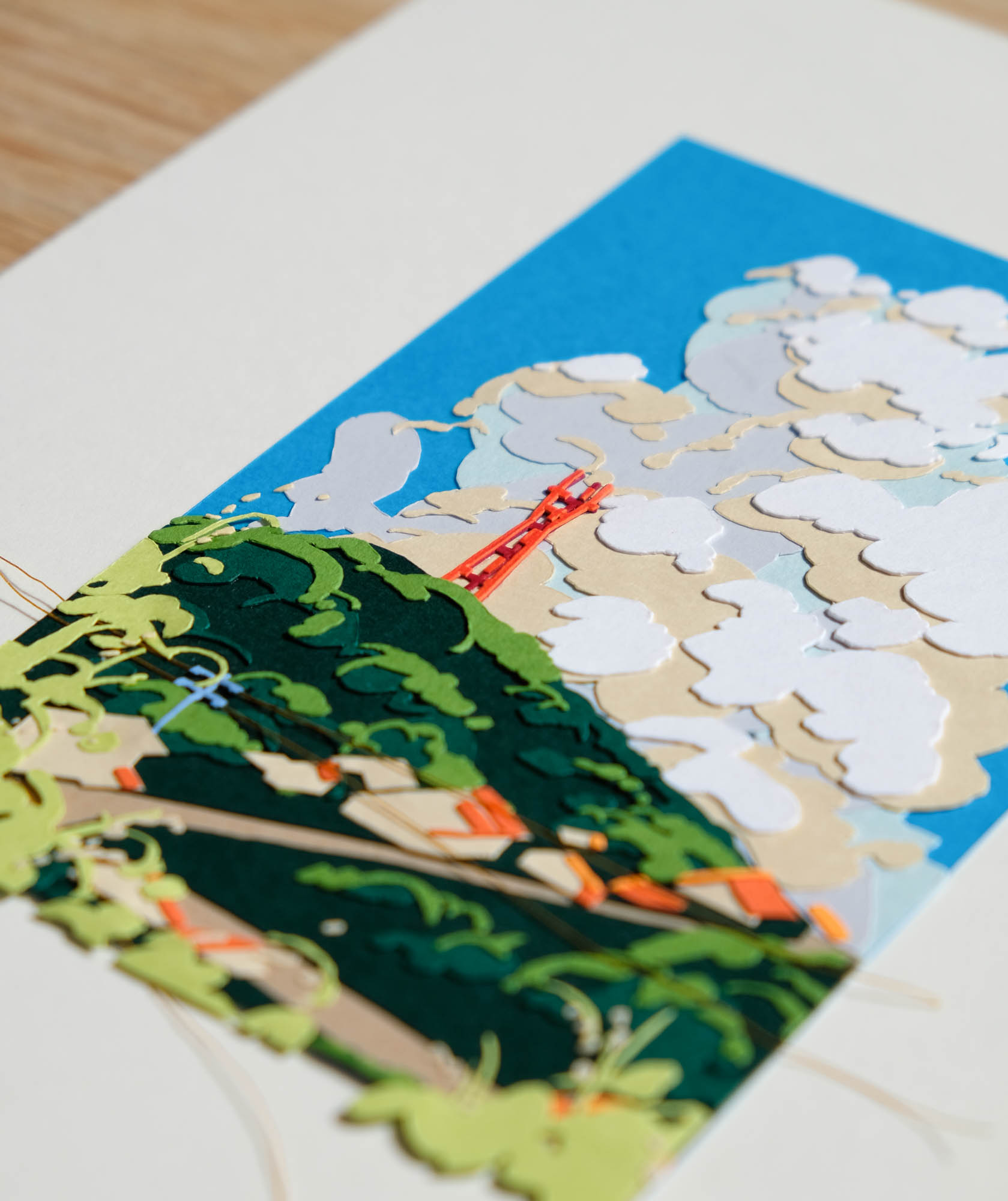 A close up view of the paper artwork reveals the layers of orange and red paper used to create Sutro Tower, as well as the layers of papers and threads that form the background.