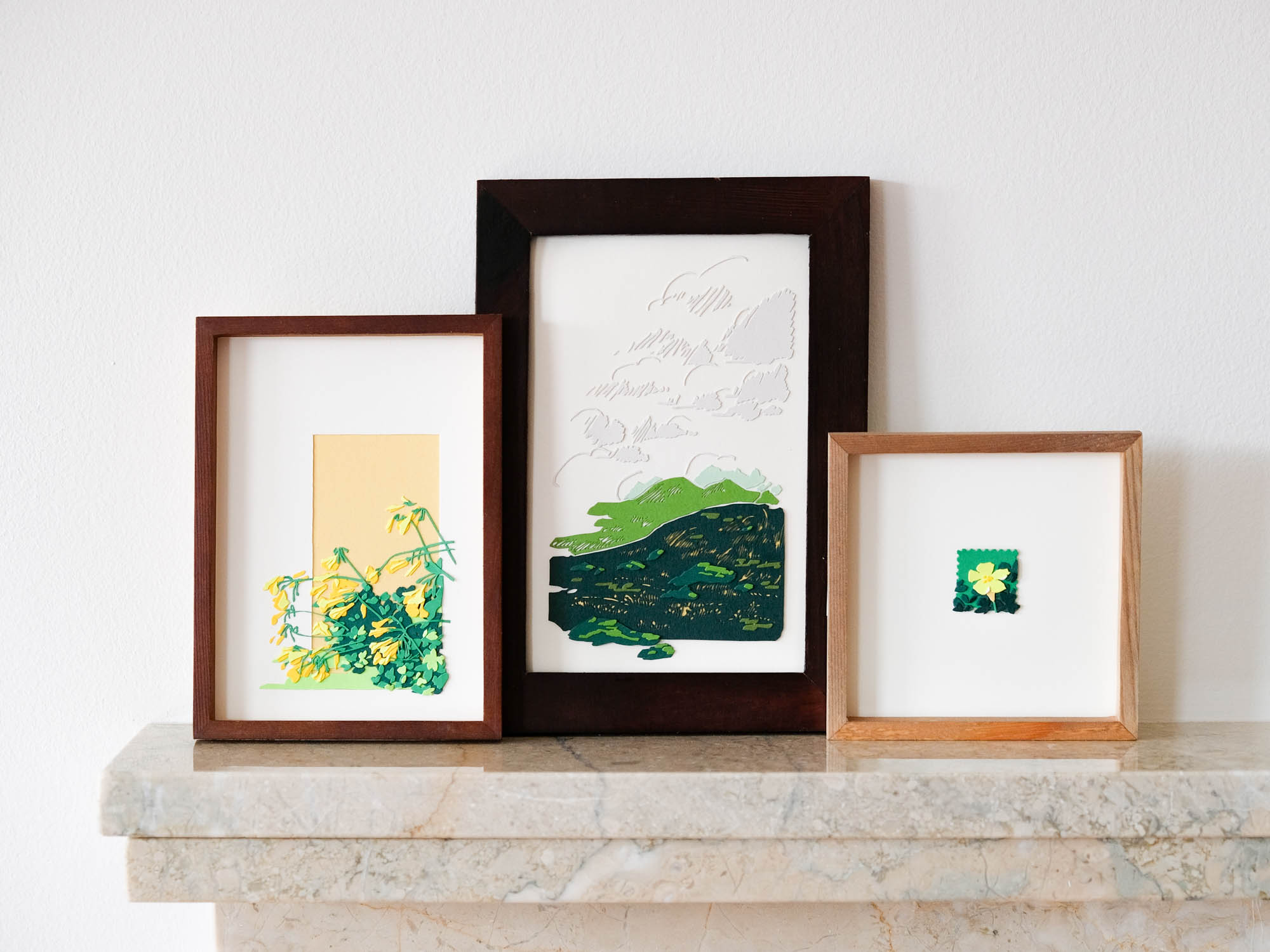 All three artworks from the Oxalis in Spring series are lined up on a marble mantel against a white wall.
