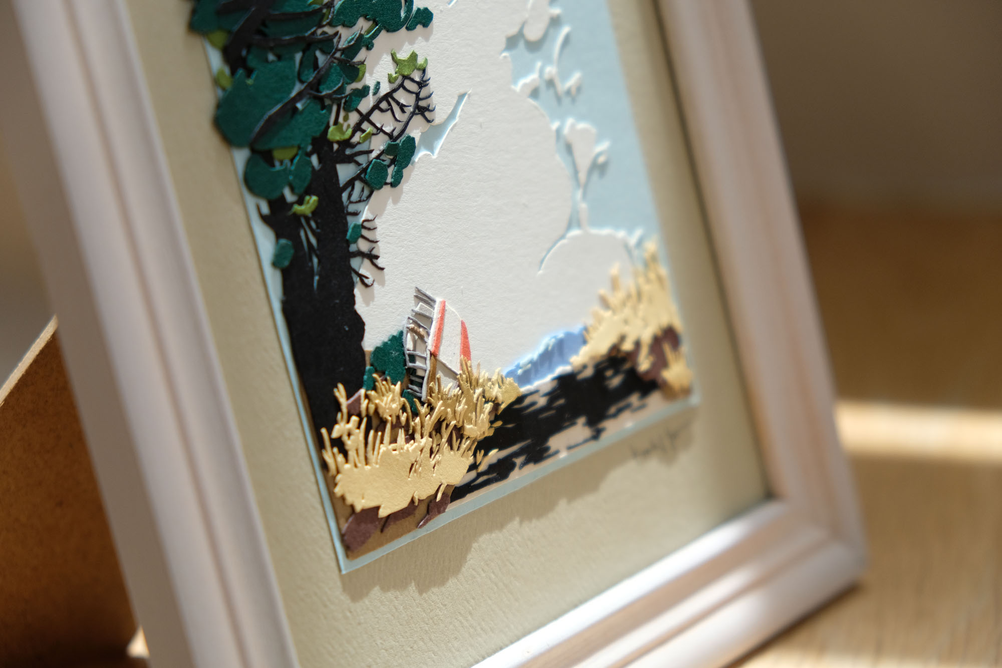 A closeup of the artwork provides a detailed view of the boat, the grasses, and the dappled sunlight on the road.