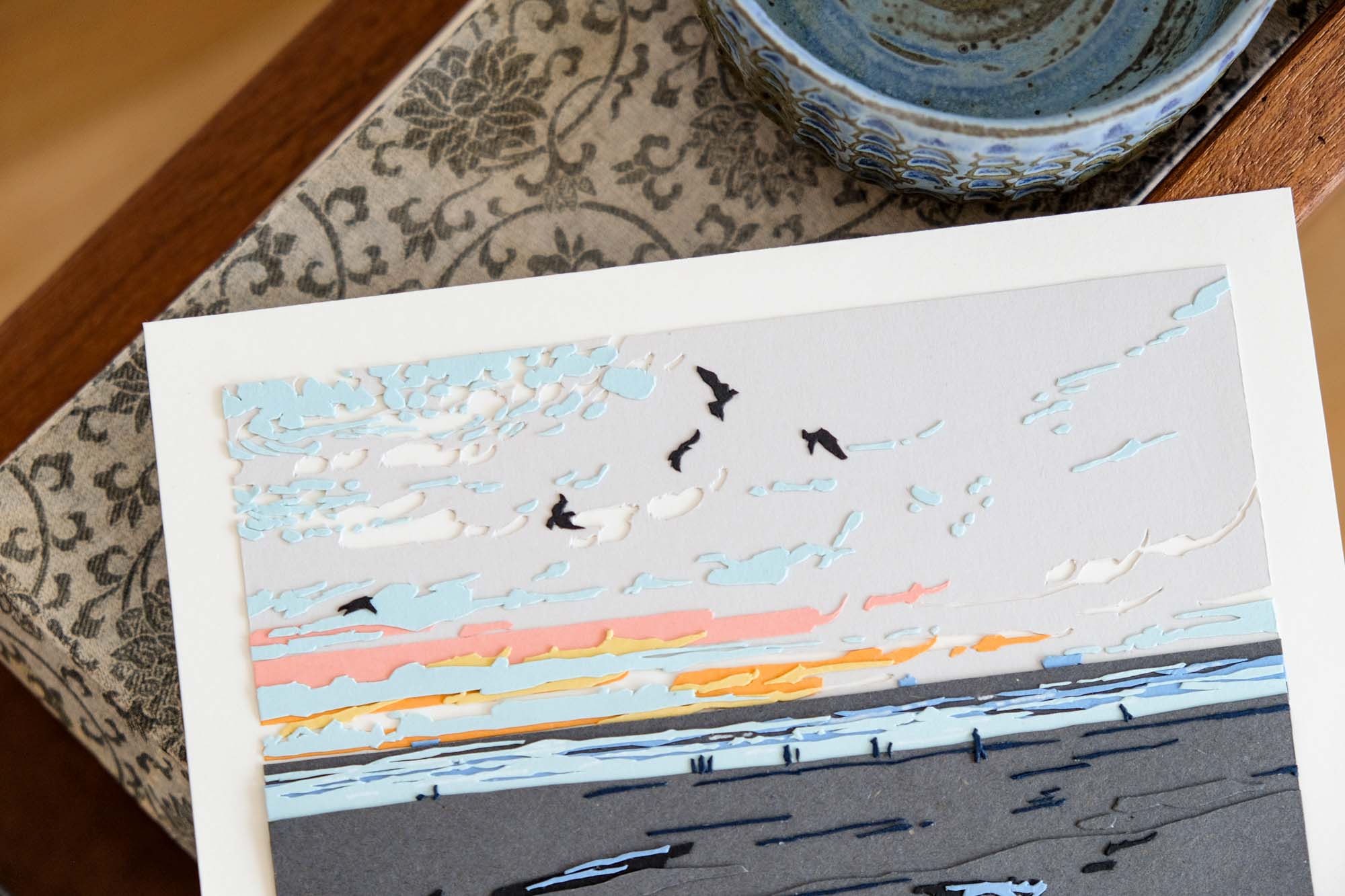 An angled view of the artwork focuses on the tiny people walking along the beach, each one barely a couple of millimeters tall.